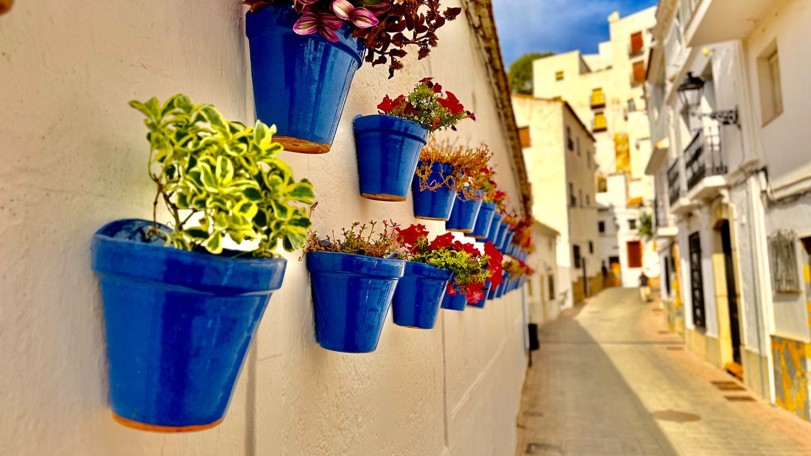 Calle de Casares con macetas azules en la pared encalada