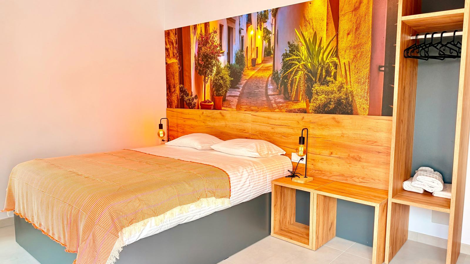 Habitación doble con cama de matrimonio y mural de una calle de Casares