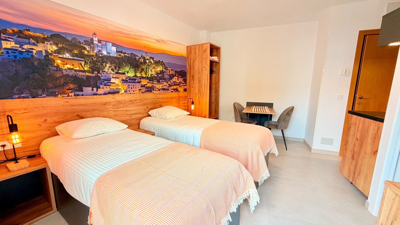 Habitación twin con dos camas y mural de Casares iluminado de noche